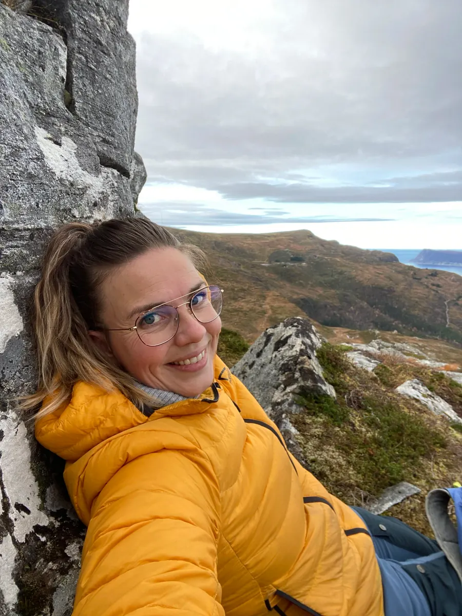 Beate Stavdal Riise i gul jakke, sittende i fjellsiden