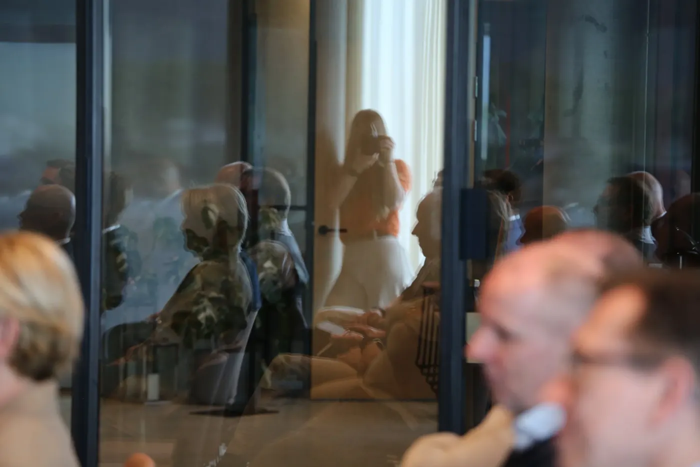 Mennesker samlet innenfor et stort vindu, sett utenfra under et fotooppdrag
