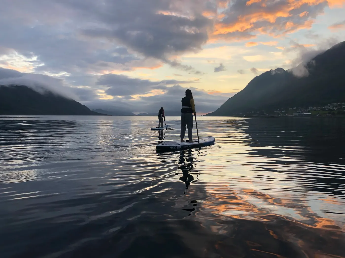 To personer på padlebrett på blank fjord