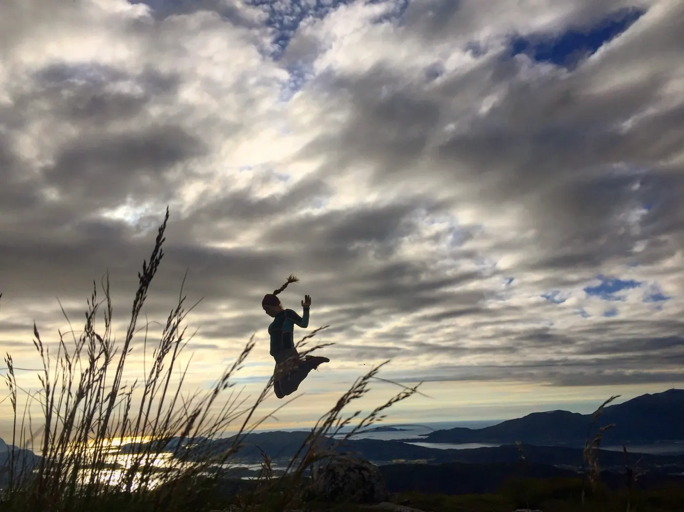 Person som hopper på en fjellrygg under en dramatisk himmel