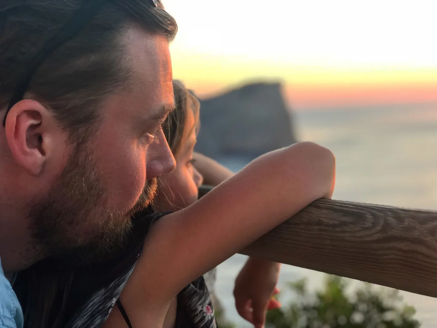 To personer lener seg mot et rekkverk og ser utover fjorden
